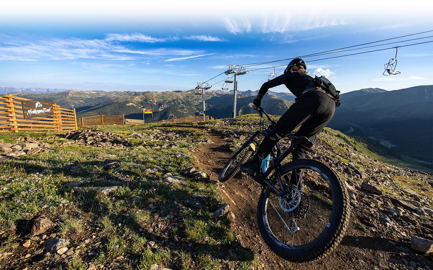a person mountain biking at A-Basin with the mountain view in the background